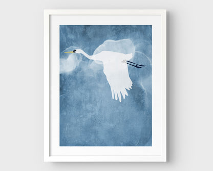 Minimalist white framed print of a white heron flying with wings lowered against a textured blue sky with soft, cloud-like forms in the background.