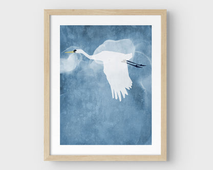 Minimalist natural wood framed print of a white heron flying with wings lowered against a textured blue sky with soft, cloud-like forms in the background.