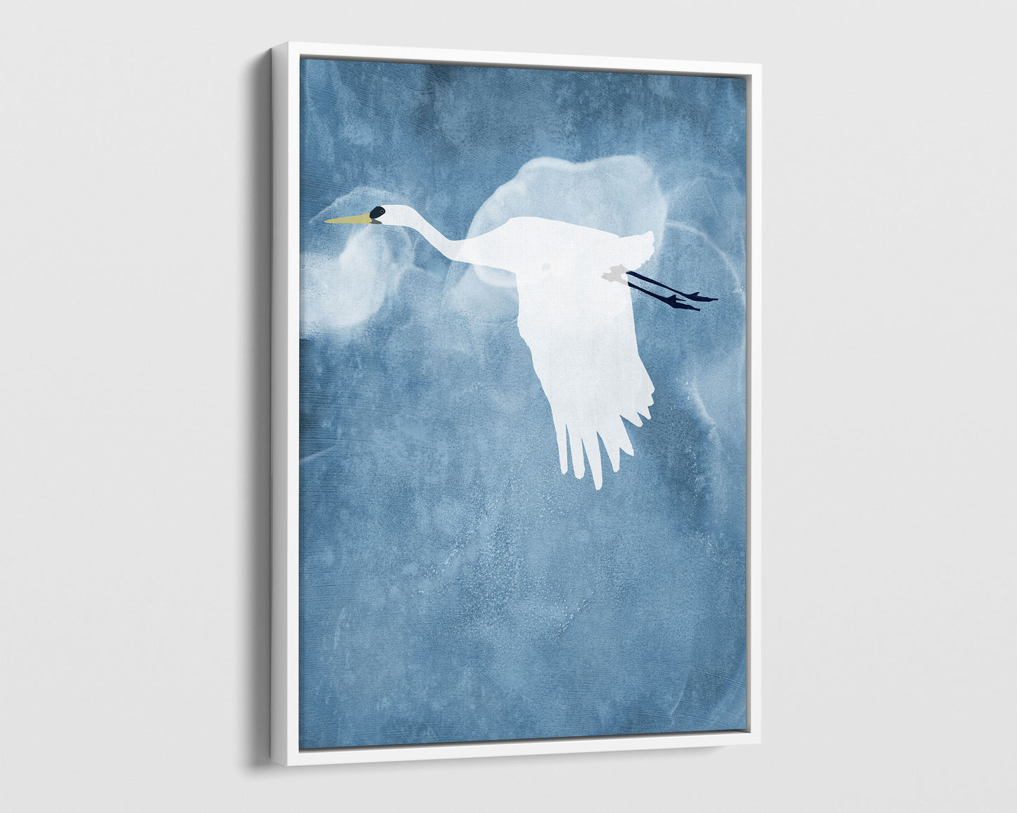 White framed canvas print of a white heron in flight with wings lowered, set against a textured blue background with soft cloud-like swirls.