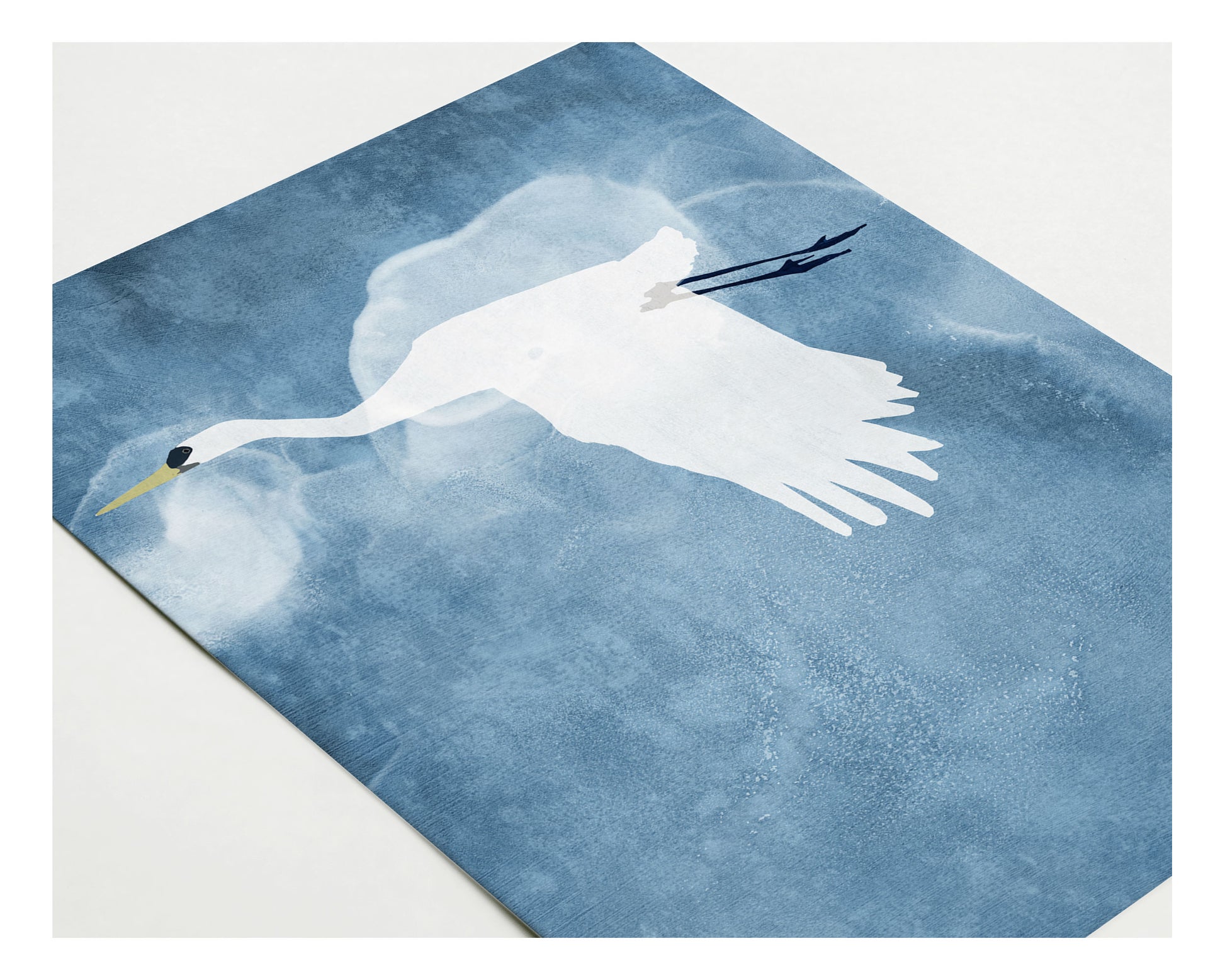 Close-up of a greeting card featuring a stylized white heron in flight against a deep blue, textured background with soft cloud-like shapes.