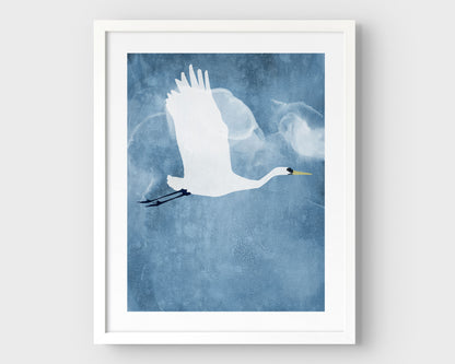 White framed vertical print of a white heron in flight with wings raised, set against a textured blue background with cloud-like forms.