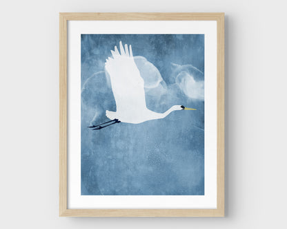 Natural wood framed vertical print of a white heron in flight with wings raised, set against a textured blue background with cloud-like forms.