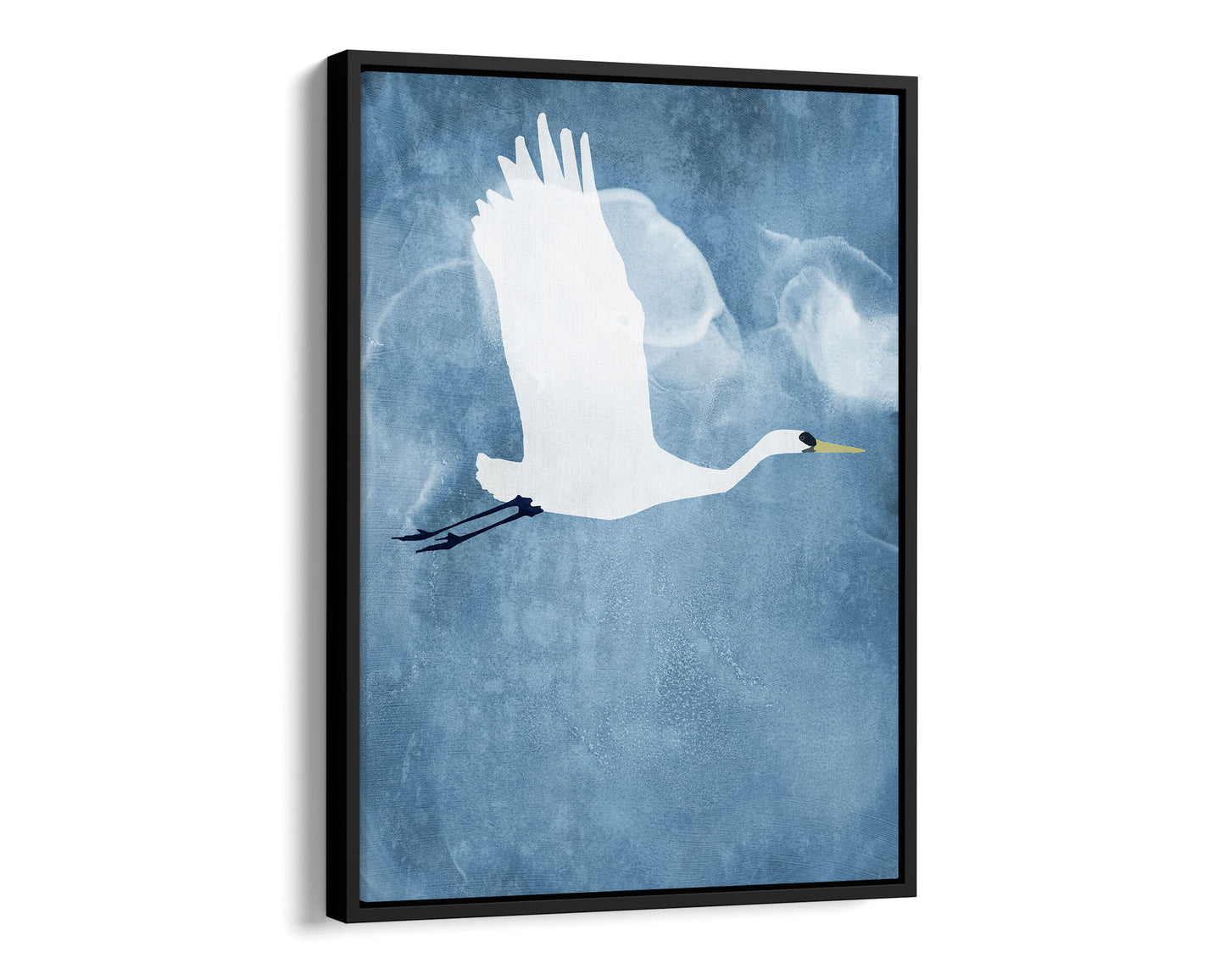 Black framed canvas print of a white heron in mid-flight with wings raised, soaring against a textured blue sky with faint, cloud-like swirls.