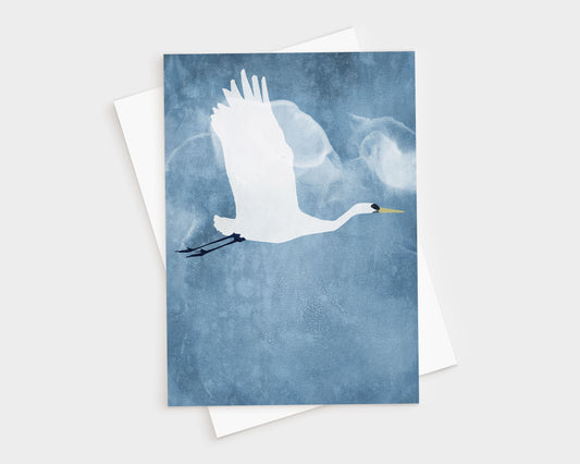 Greeting card featuring a white heron in flight with wings raised against a misty blue textured background, paired with a white envelope.