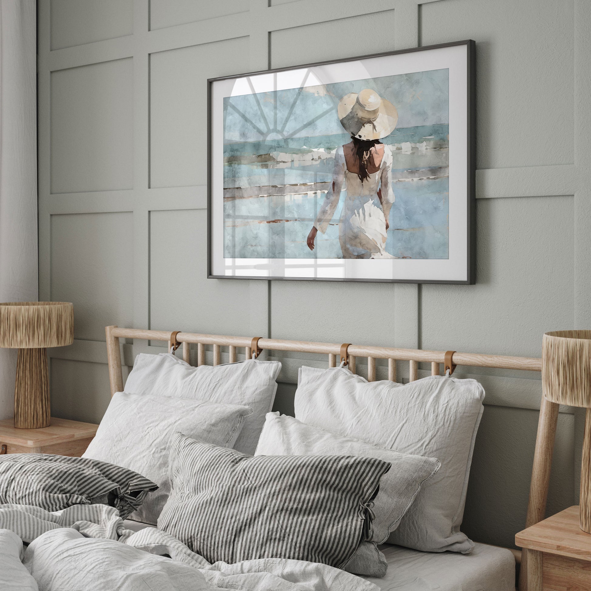 Framed watercolor painting of a woman in a white dress and hat displayed on a wall above a neatly made bed with light gray bedding and striped pillows in a modern bedroom.