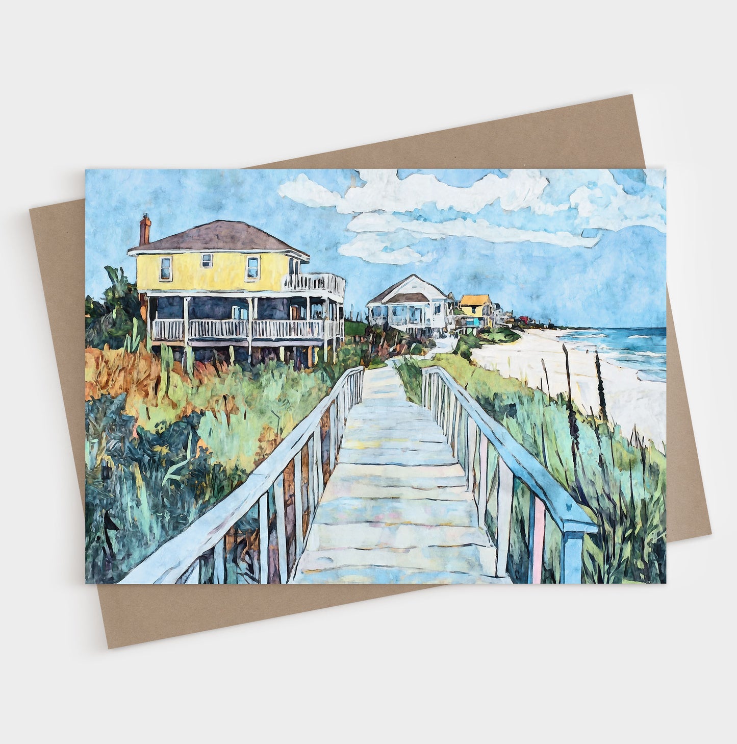 Folded greeting card featuring a vibrant watercolor-style illustration of a coastal boardwalk leading past colorful beach houses toward the ocean. A bright yellow house stands out in the foreground, framed by sea oats, greenery, and soft blue skies, capturing the relaxed charm of a seaside neighborhood.
