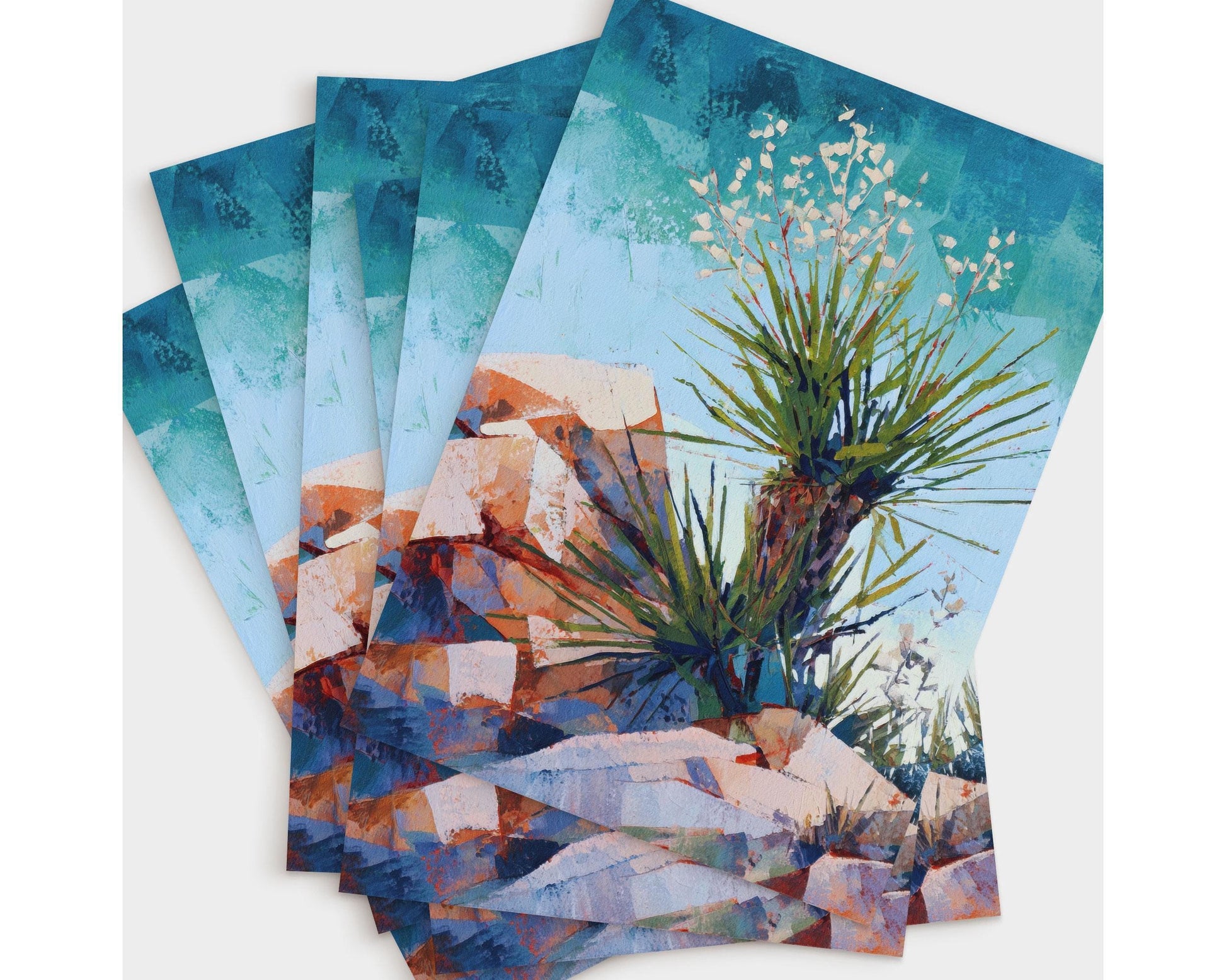 Set of greeting cards featuring a vibrant desert painting of a yucca plant with spiky green leaves and delicate white blossoms, surrounded by red and orange rocky terrain under a vivid blue sky.