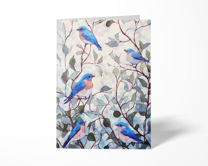 Folded greeting card featuring a watercolor illustration of five bluebirds with peachy chests perched among slender brown branches and soft green leaves against a pale, textured background.