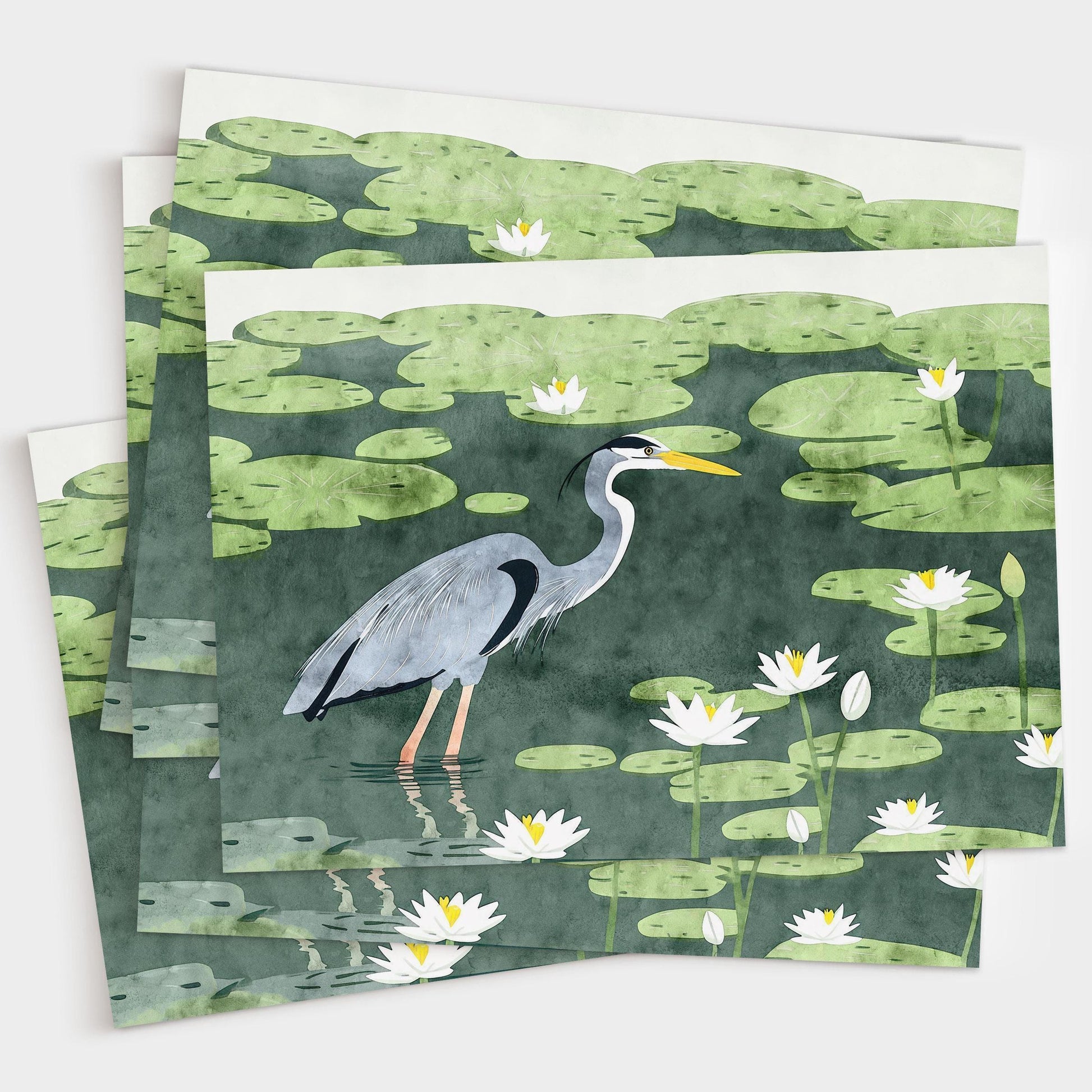 Stack of greeting cards featuring an illustration of a great blue heron standing in a pond filled with lily pads and white water lilies. The cards are slightly fanned out on a white background, showcasing the consistent, vibrant nature-themed design.