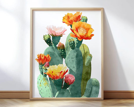 Watercolor art print of a prickly pear cactus with large blooming flowers in shades of orange, yellow, pink, and red, set against a white background and displayed in a light wood frame.