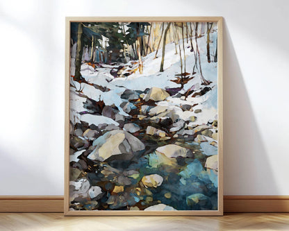 Framed watercolor-style painting of a snowy forest scene, featuring a rocky stream with reflections of blue and green tones. Bare trees rise from the snow-covered ground, with sunlight filtering through in the background. The artwork is displayed leaning against a white wall on a wooden floor.