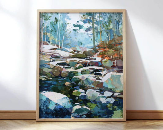 Framed art print of a modern impressionist forest stream scene, featuring cool blues and greens with accents of warm rust tones. The painting shows light filtering through trees and glinting off rocks and water, creating a serene woodland atmosphere. Displayed in a natural wood frame leaning against a white wall on a hardwood floor.