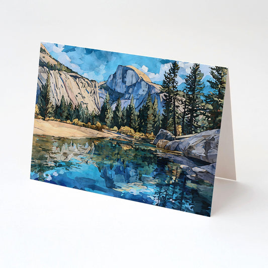 Folded greeting card featuring a watercolor-style landscape of Yosemite’s Half Dome, with tall pine trees, rocky cliffs, and a vivid blue river reflecting the scene, set against a bright sky.