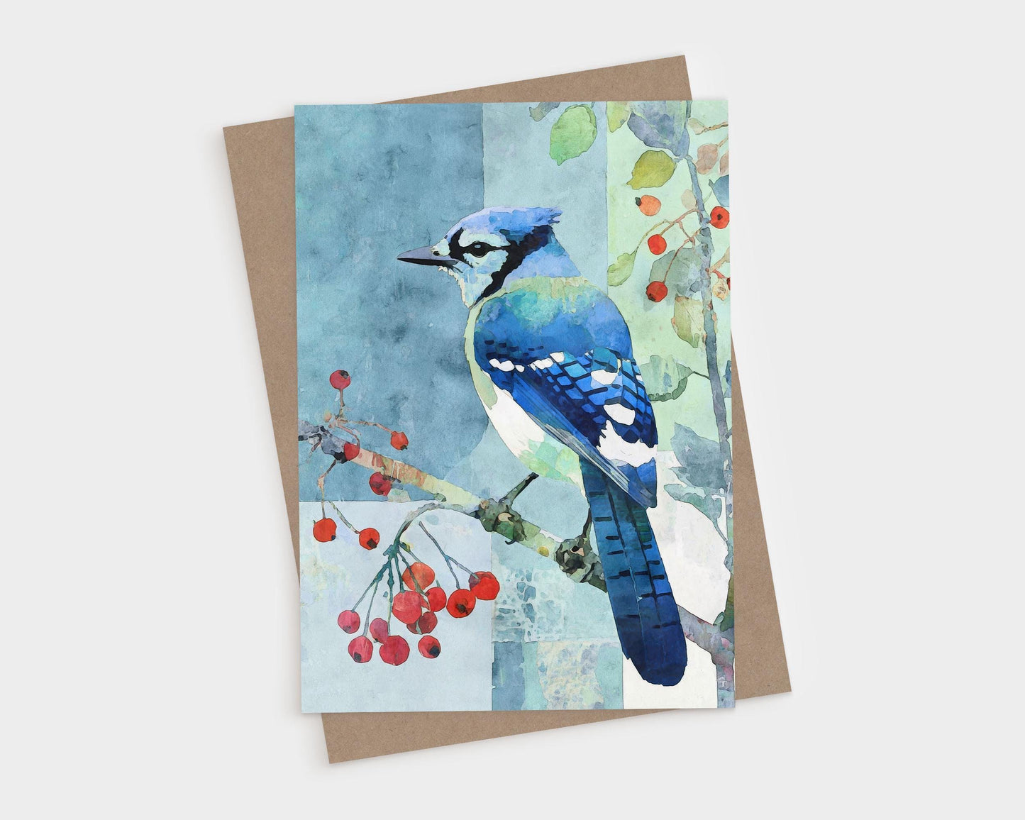 Watercolor illustration of a blue jay perched on a branch with red berries, set against a soft patchwork-style background of blue and green tones. The card rests on a brown kraft paper envelope, evoking a natural, serene feel perfect for all-occasion correspondence.