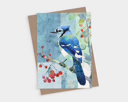 Watercolor illustration of a blue jay perched on a branch with red berries, set against a soft patchwork-style background of blue and green tones. The card rests on a brown kraft paper envelope, evoking a natural, serene feel perfect for all-occasion correspondence.