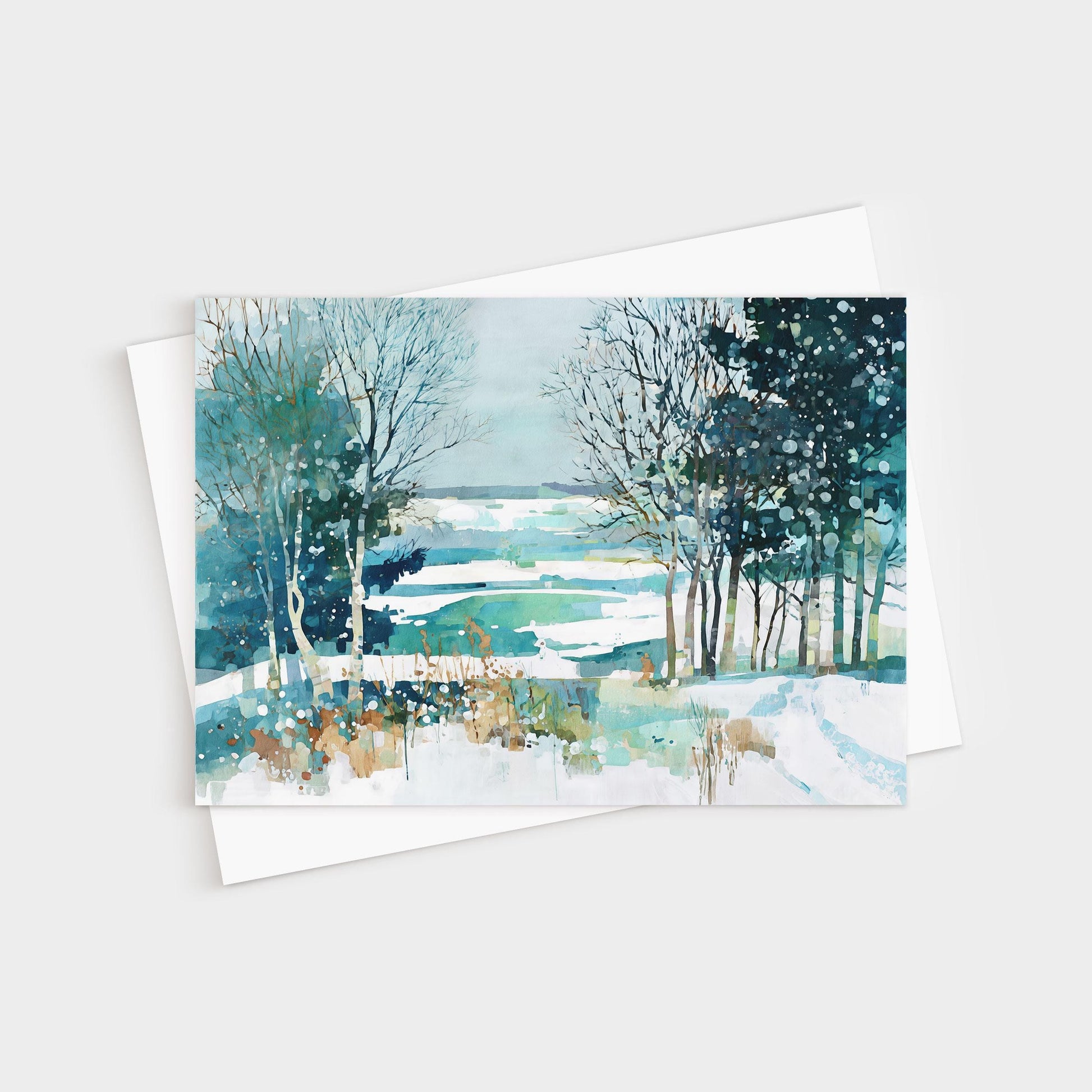 Watercolor greeting card featuring a serene winter landscape with snow-covered fields, bare trees, and evergreens in shades of blue, teal, and white, with soft brushstrokes and splattered paint suggesting falling snow. Card is displayed with a white envelope.