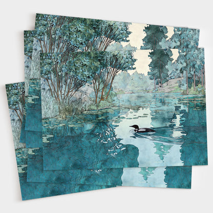 Set of greeting cards featuring a watercolor-style illustration of a loon gliding across a calm lake surrounded by trees. The overlapping cards display rich teal and green tones with soft reflections in the water, creating a serene, nature-inspired design.