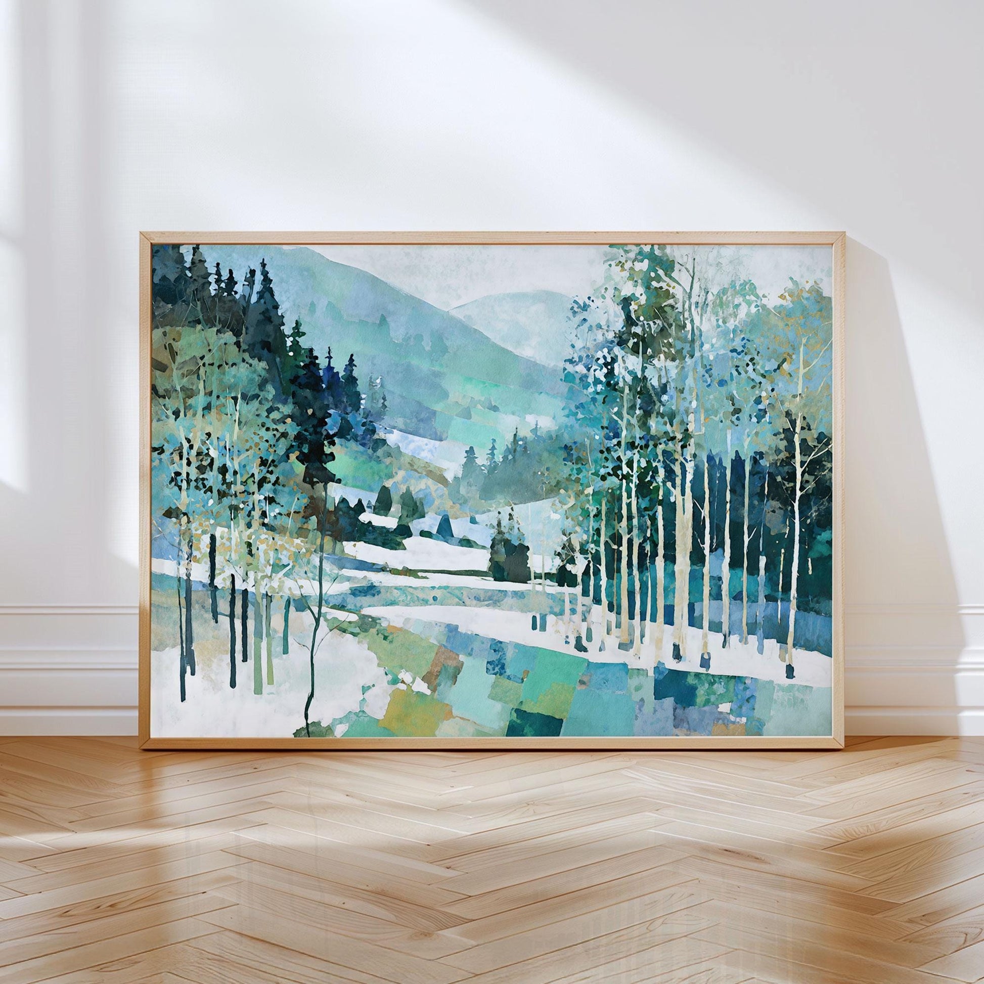 Framed painting of a serene mountain landscape with snow, pine trees, and birch trees in shades of blue, green, and white. The artwork features a geometric, patchwork effect at the base and soft gradients in the hills, creating a modern impressionist style. Displayed in a light wood frame and leaning against a white wall on a polished wood floor with sunlight streaming in.