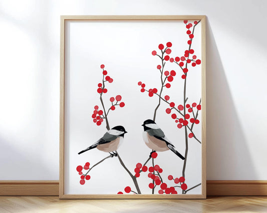 Minimalist art print featuring two chickadees perched on delicate brown branches with clusters of bright red winter berries. The birds’ soft black, white, and beige plumage contrasts beautifully with the crisp white background and vivid berries. Displayed in a light wood frame, the artwork exudes a calm, modern, and nature-inspired aesthetic perfect for seasonal or year-round decor.